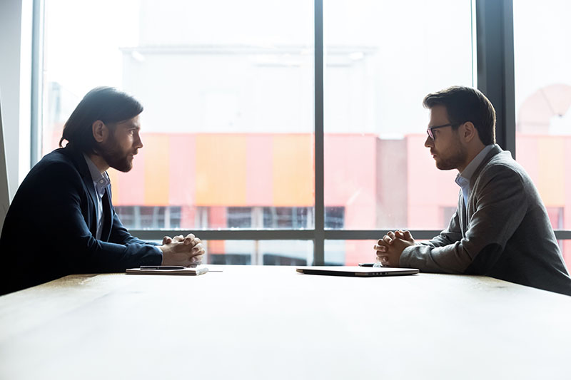 Two Men sitting across from each other at a table.